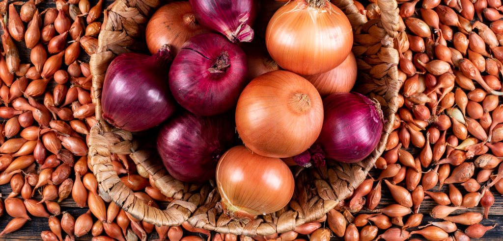 Onions in a basket with red onions top view on a shallots background