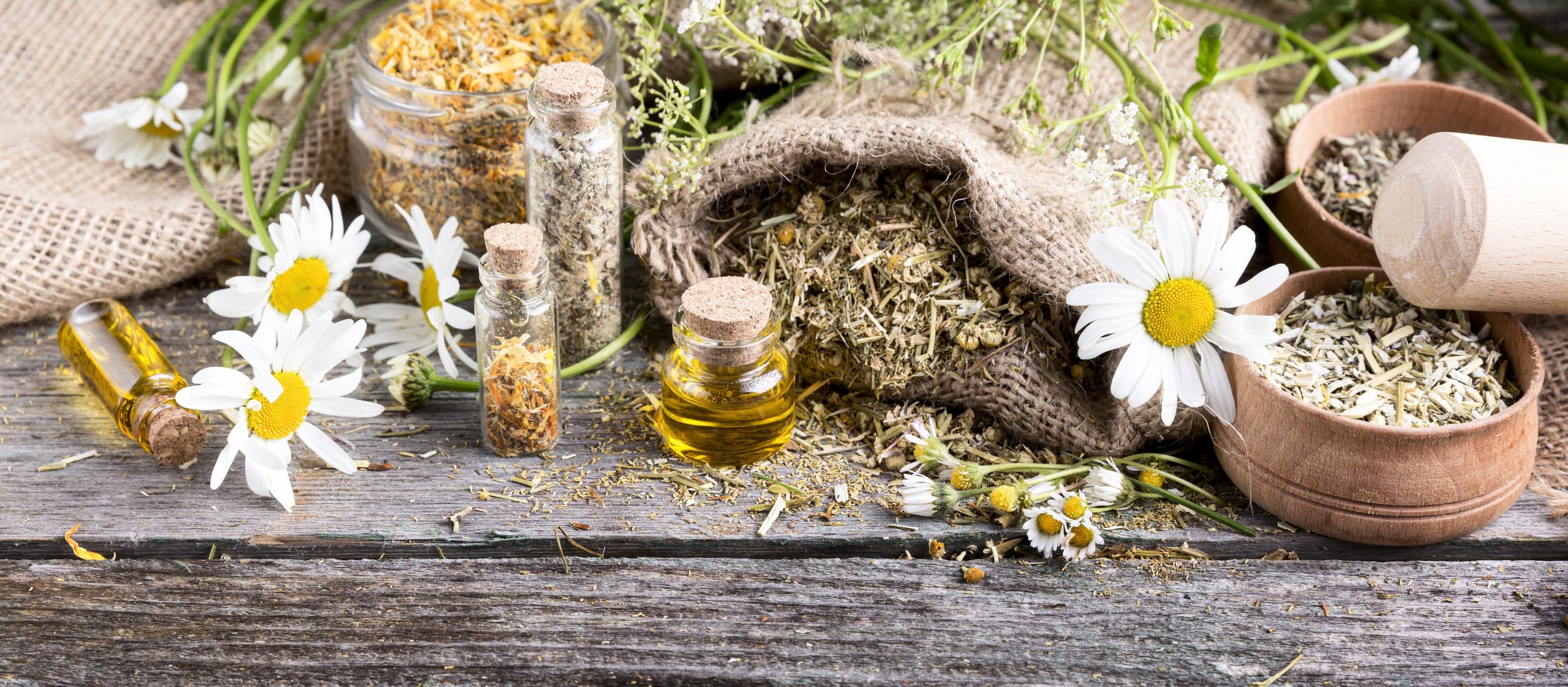 high-angle-natural-medicine-wooden-table chamomile flowers and oil
